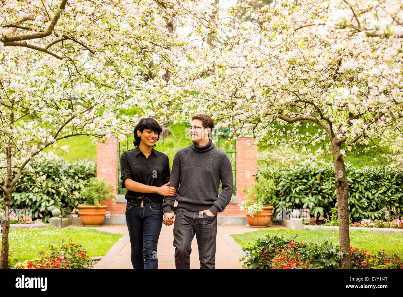 Couple en train de marcher sous les arbres en fleurs dans le parc Banque D'Images