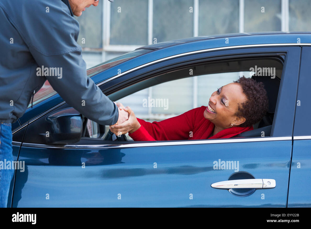 Les amis se serrer la main à travers la fenêtre de voiture Banque D'Images