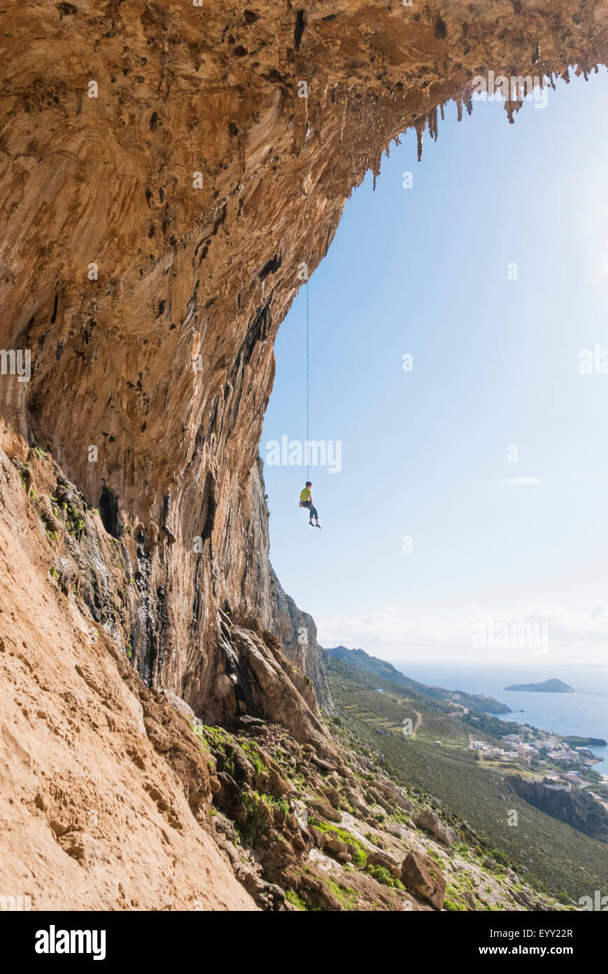 Caucasian climber hanging from cable sur mur de pierre Banque D'Images