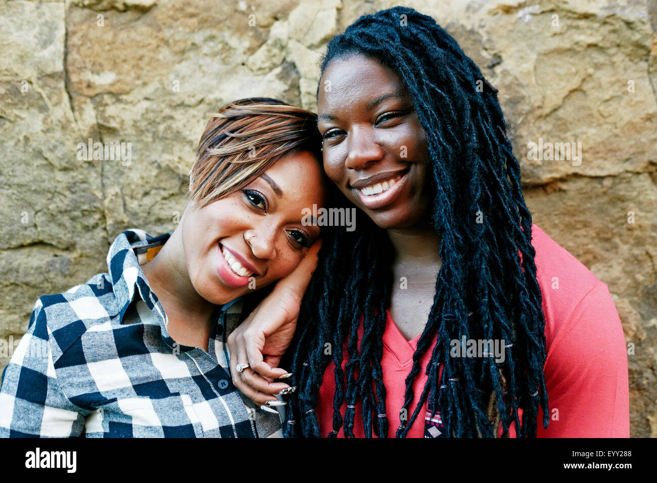 Smiling women hugging près de rock wall Banque D'Images