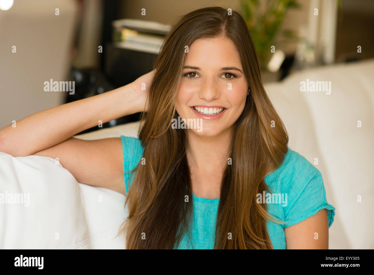 Caucasian woman with long hair sitting on sofa Banque D'Images