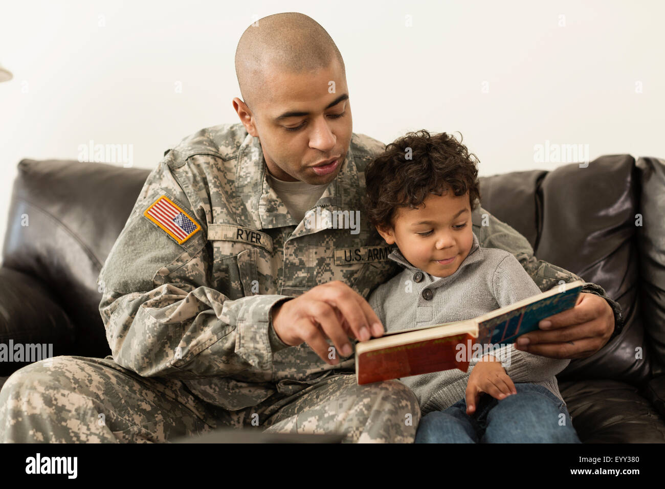 Mixed Race soldat lecture livre à fils sur canapé Banque D'Images