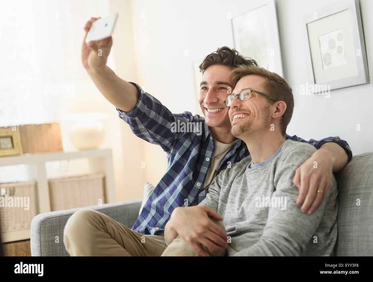 Caucasian couple gay en tenant sur canapé selfies Banque D'Images