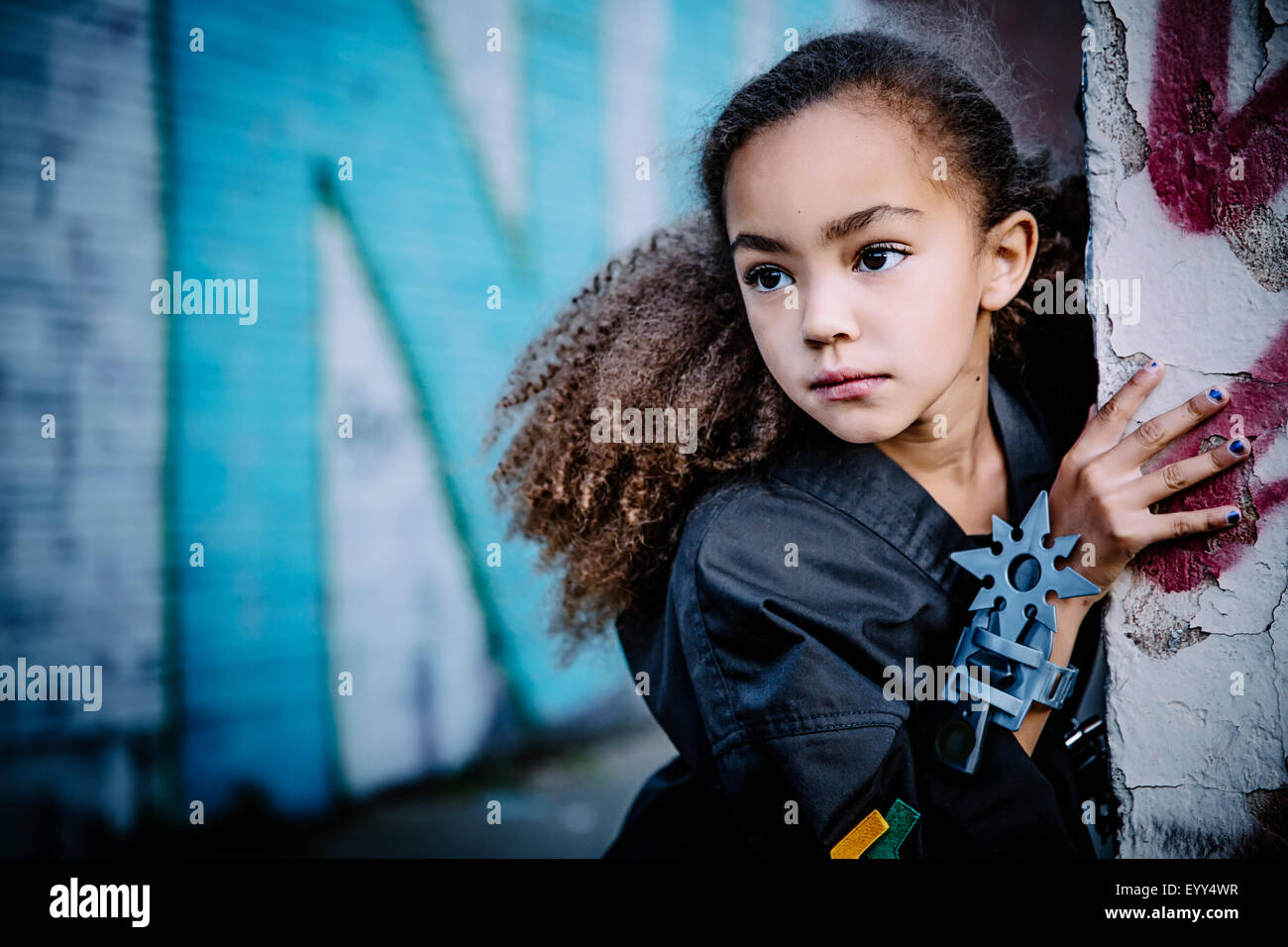 Mixed Race girl en uniforme d'arts martiaux avec pierres star peeking autour du coin Banque D'Images