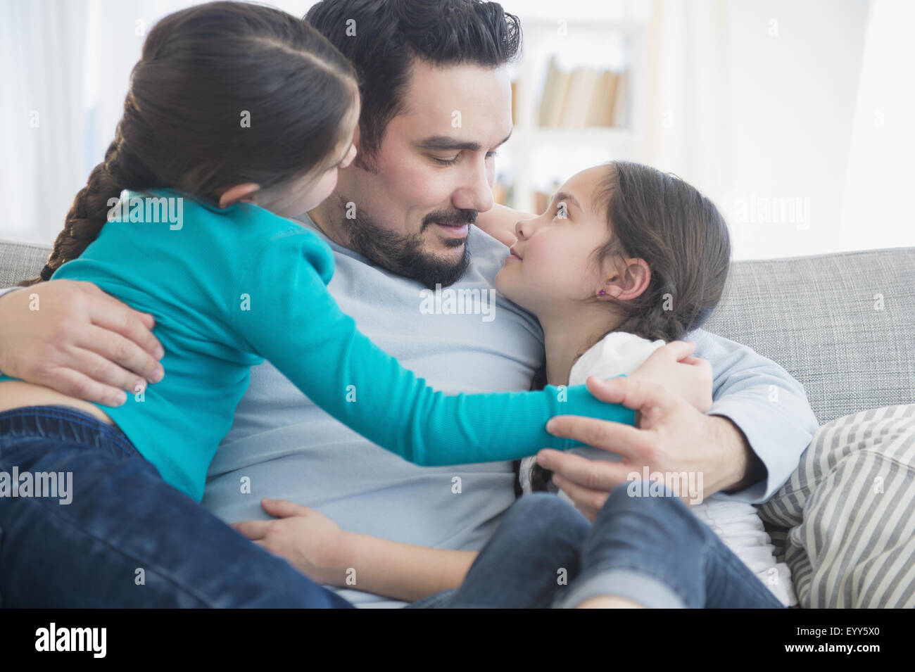 Père et filles caucasiennes hugging on sofa Banque D'Images