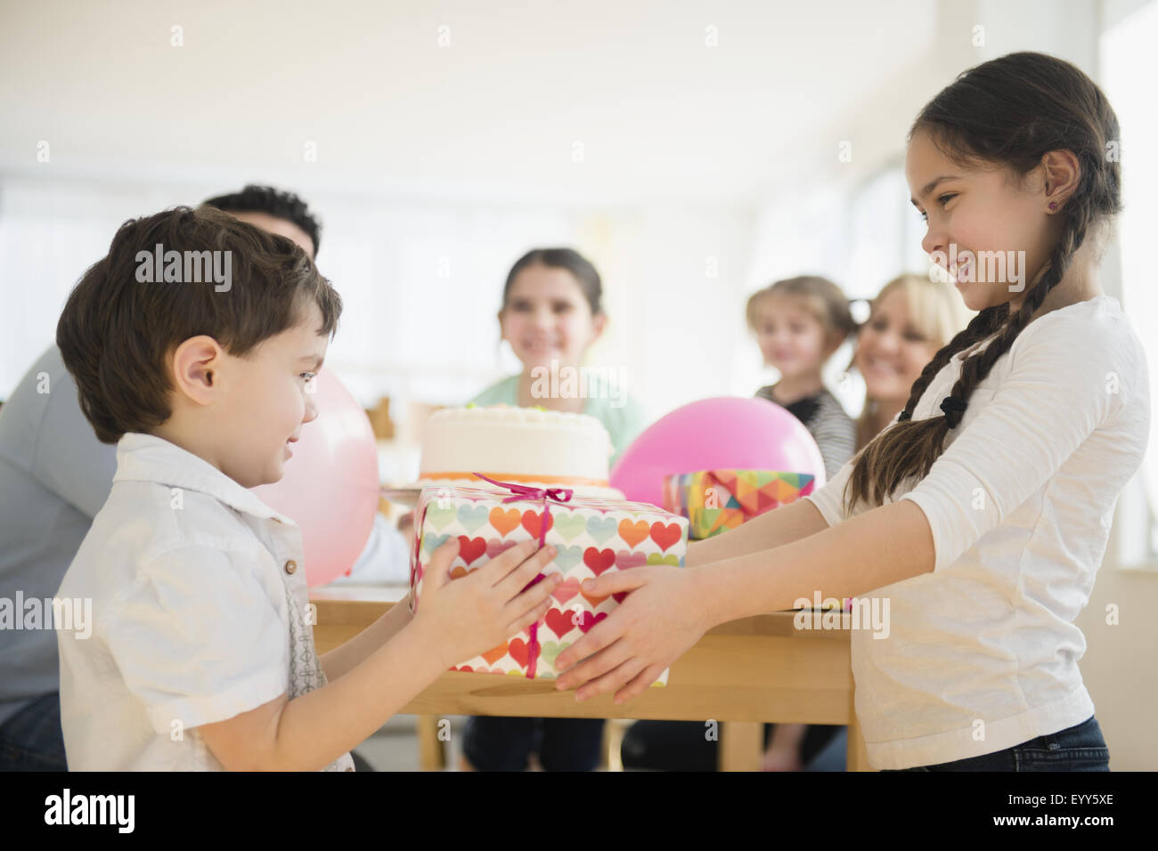 Caucasian girl donner de cadeau d'Anniversaire frère at party Banque D'Images