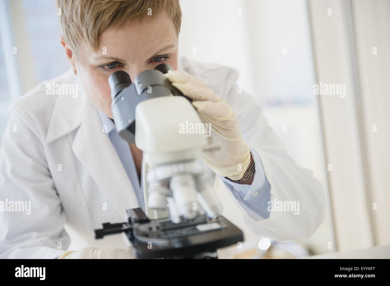 Caucasian scientist looking through microscope in lab Banque D'Images