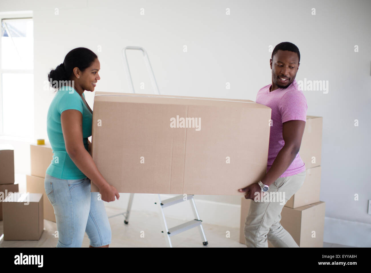 Couple carrying cardboard box in new home Banque D'Images