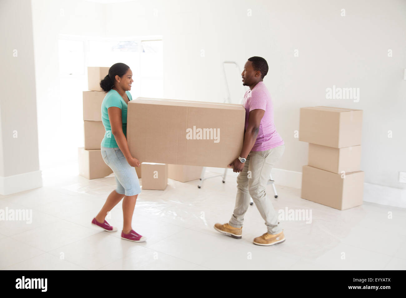 Couple carrying cardboard box in new home Banque D'Images