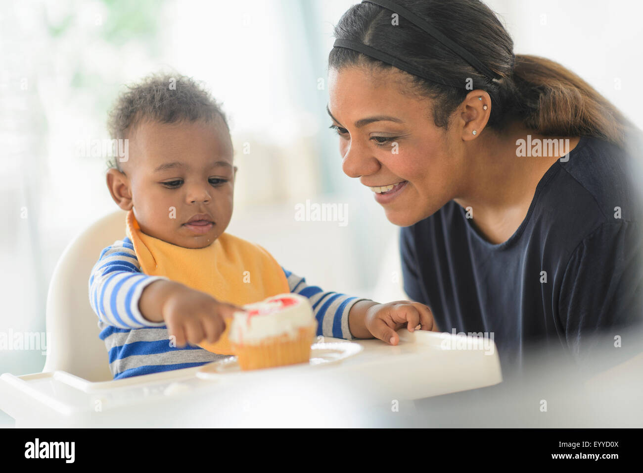 Mixed Race mother baby son cupcake dans une chaise haute Banque D'Images