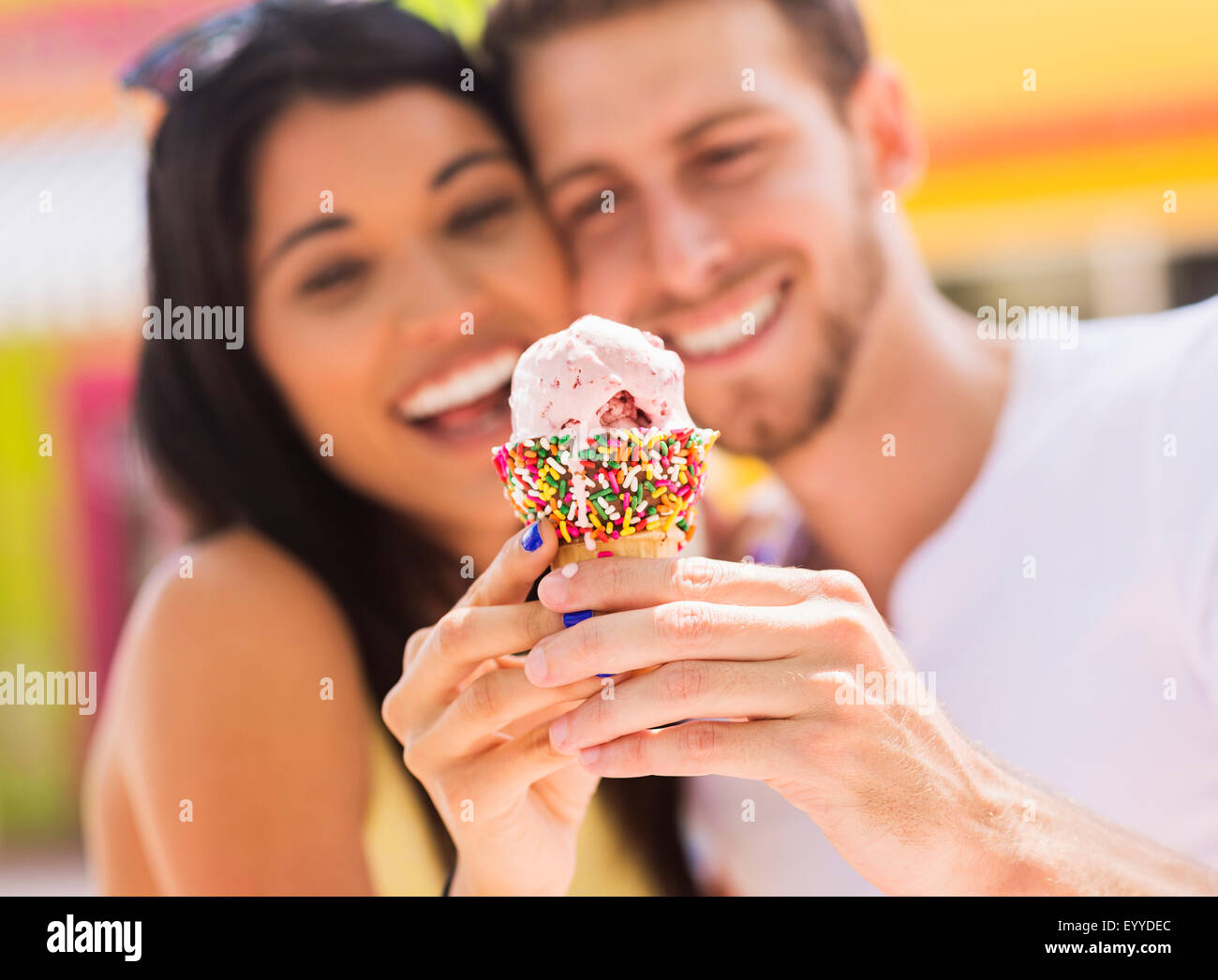 Hispanic couple partager cornet de crème glacée en plein air Banque D'Images