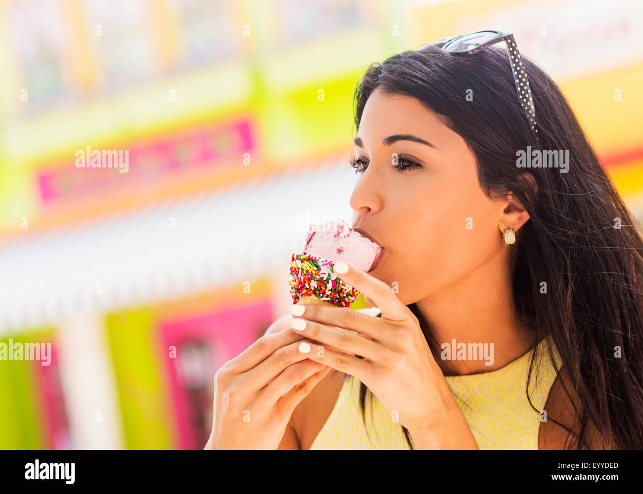 Hispanic woman eating ice cream cone en plein air Banque D'Images