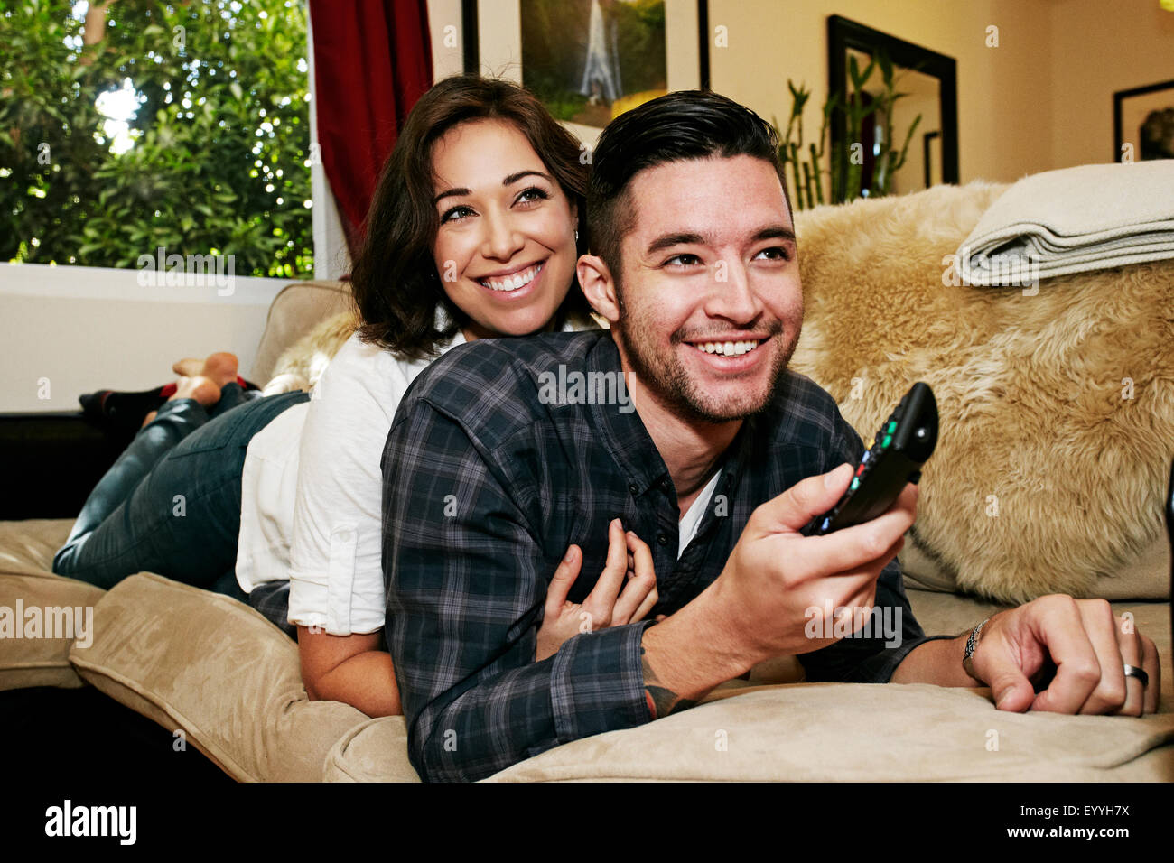Couple watching television on sofa in living room Banque D'Images
