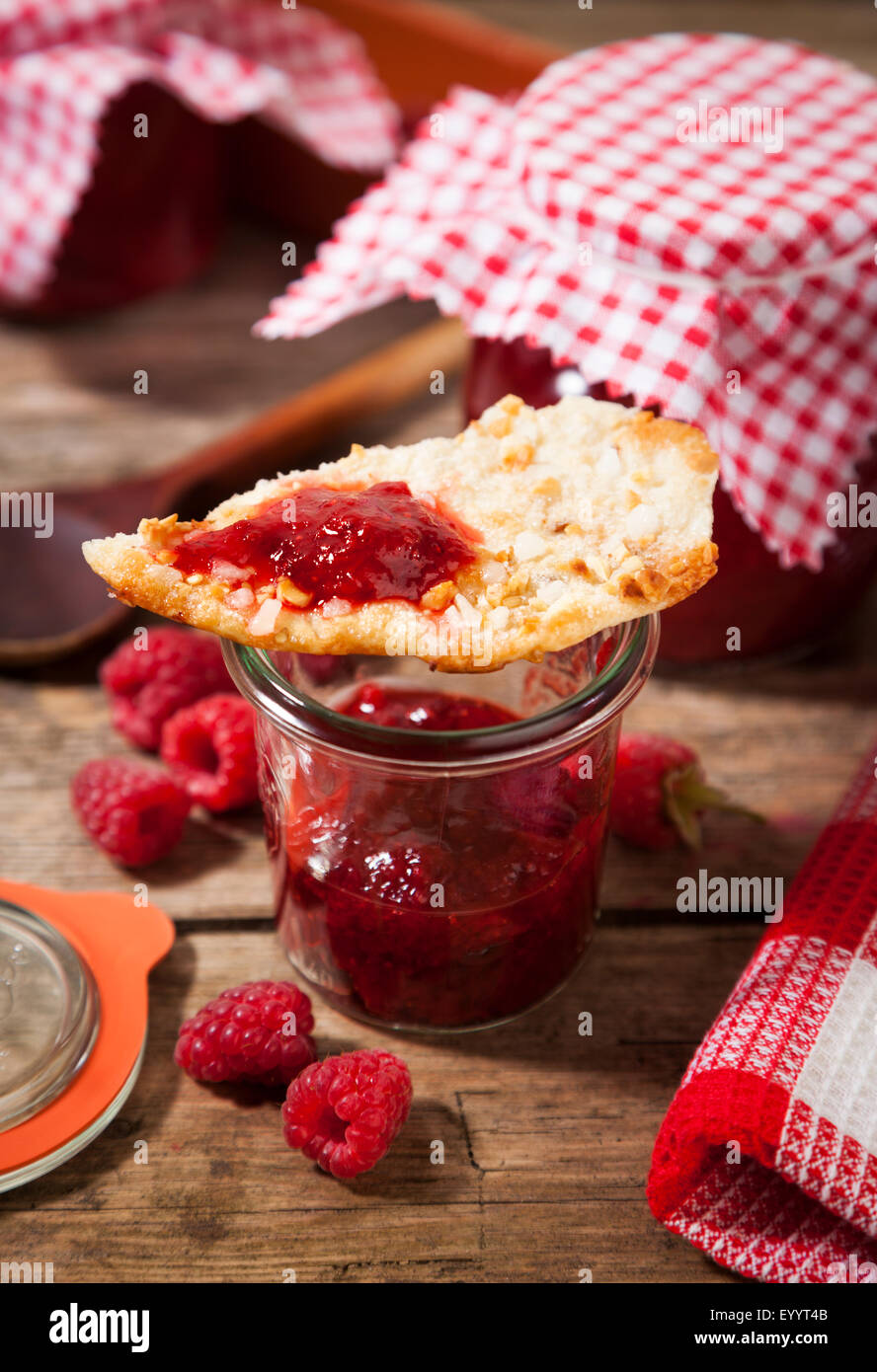 Confiture de framboises à la main dans le bocal et le biscuit aux amandes Banque D'Images