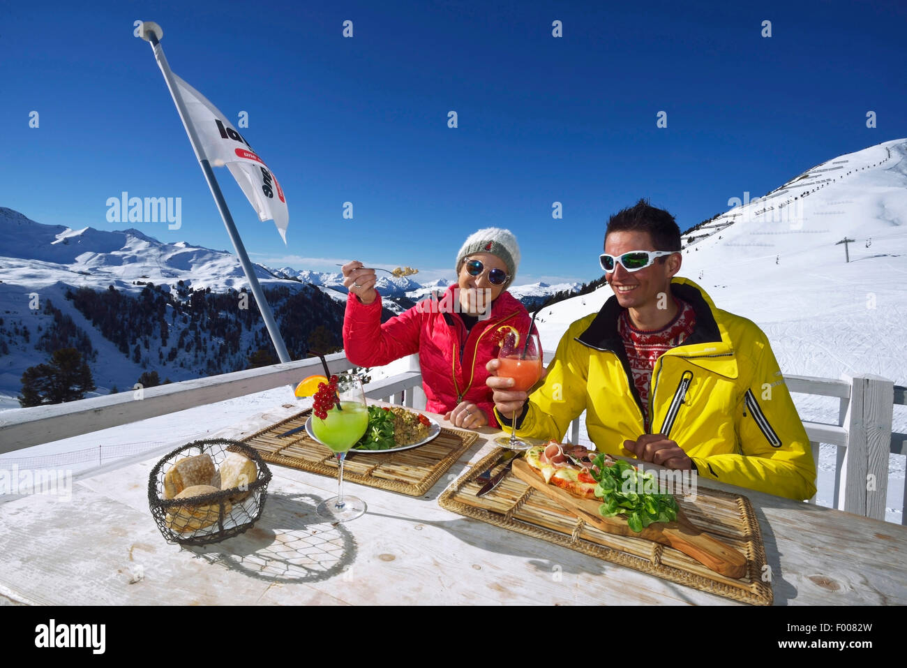 Couple avec des cocktails et des repas à la terrasse de la station de montagne, France, Savoie, La Plagne Banque D'Images