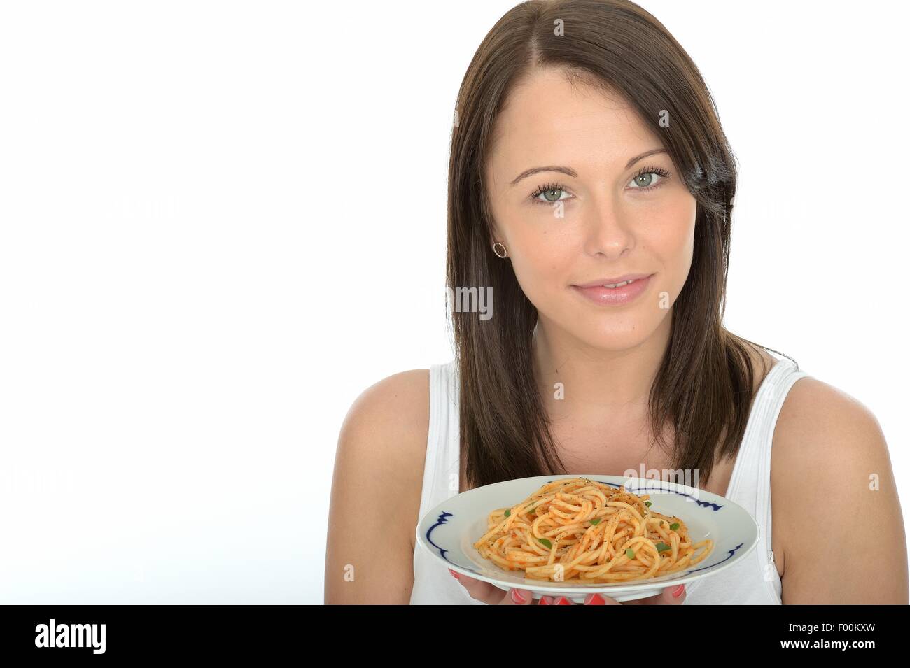 Jeune femme Positive confiante tenant une assiette de pâtes Spaghetti italien de style méditerranéen à la sauce tomate isolé sur fond blanc Banque D'Images