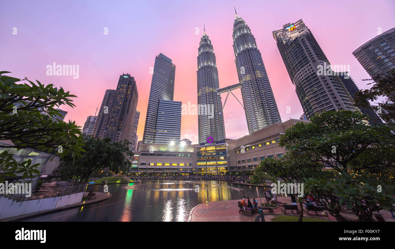 Fontaine à eau avec Suria KLCC Petronas Towers et les immeubles de bureaux à l'heure bleu coucher du soleil dans la nuit. Banque D'Images
