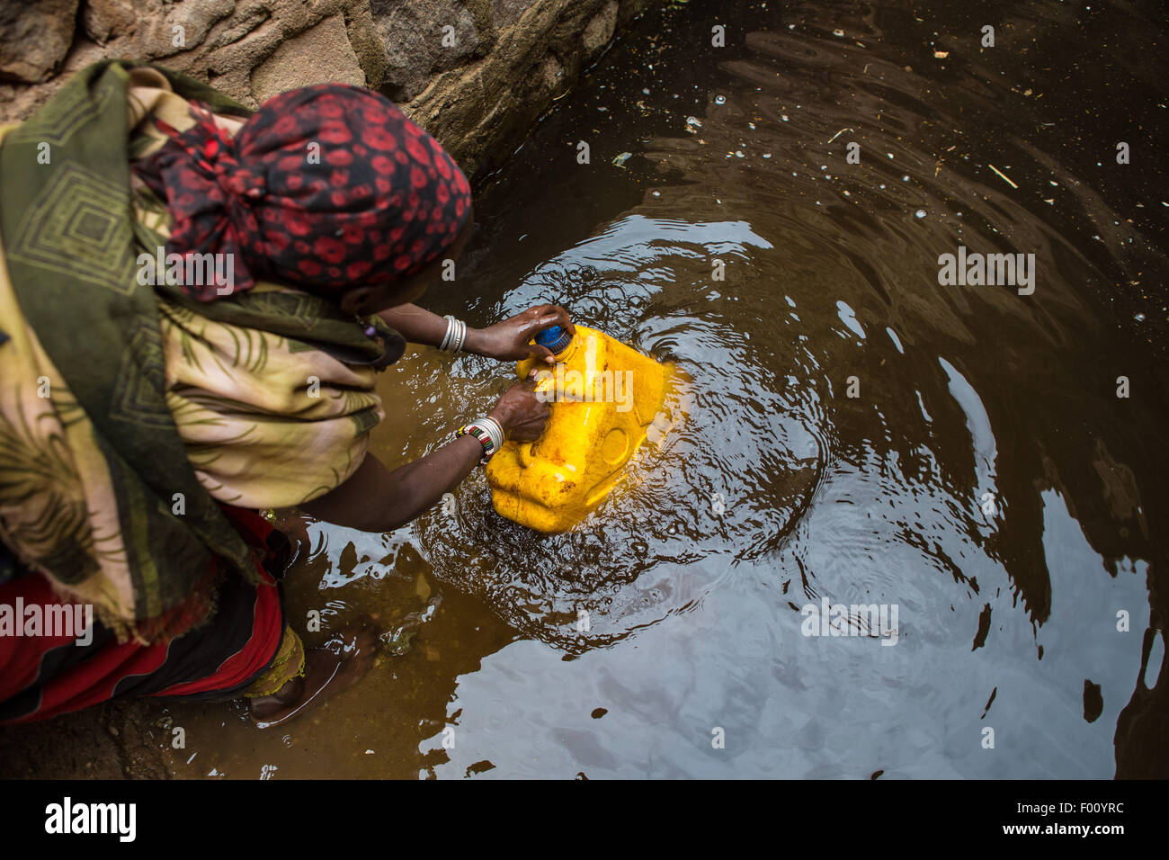 Femme prend de l'eau d'un puits avant de retourner à son village. L'eau est purifiée avec les tablettes avant de boire Banque D'Images