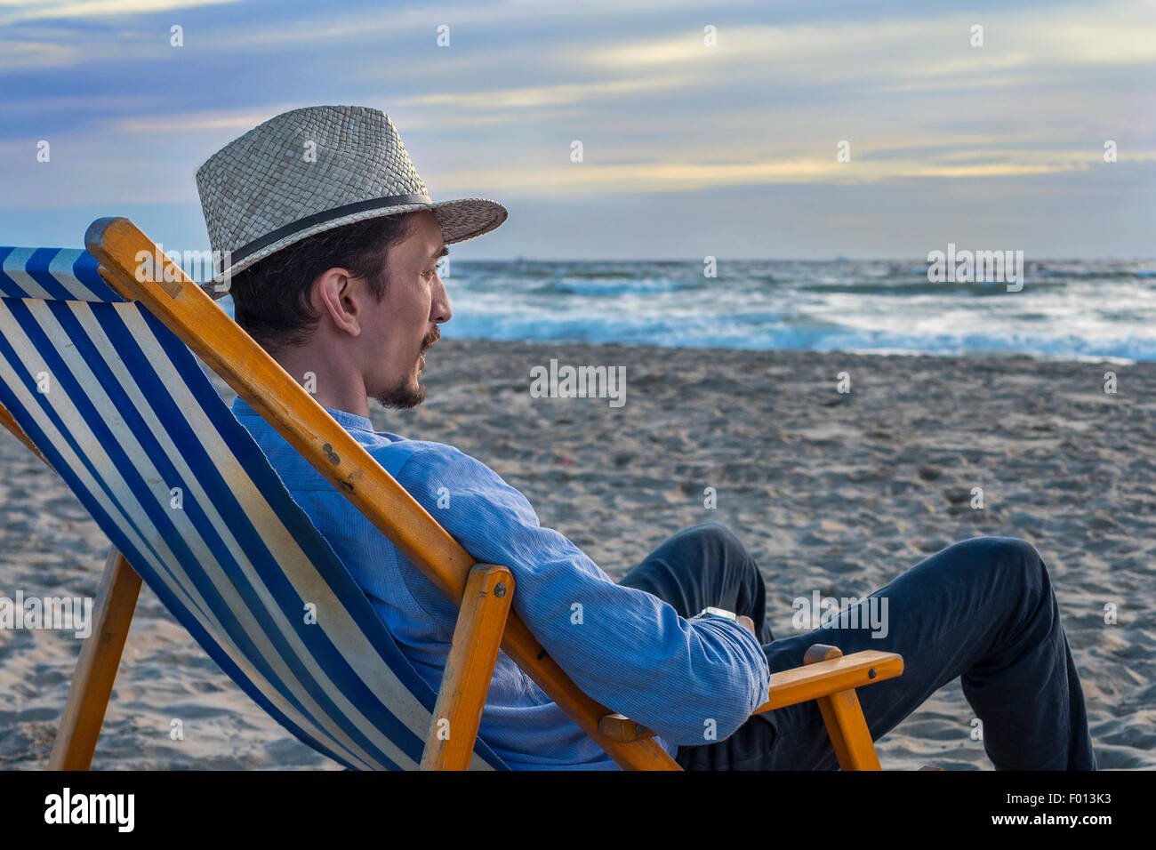 L'homme regardant le coucher du soleil sur la plage Banque D'Images