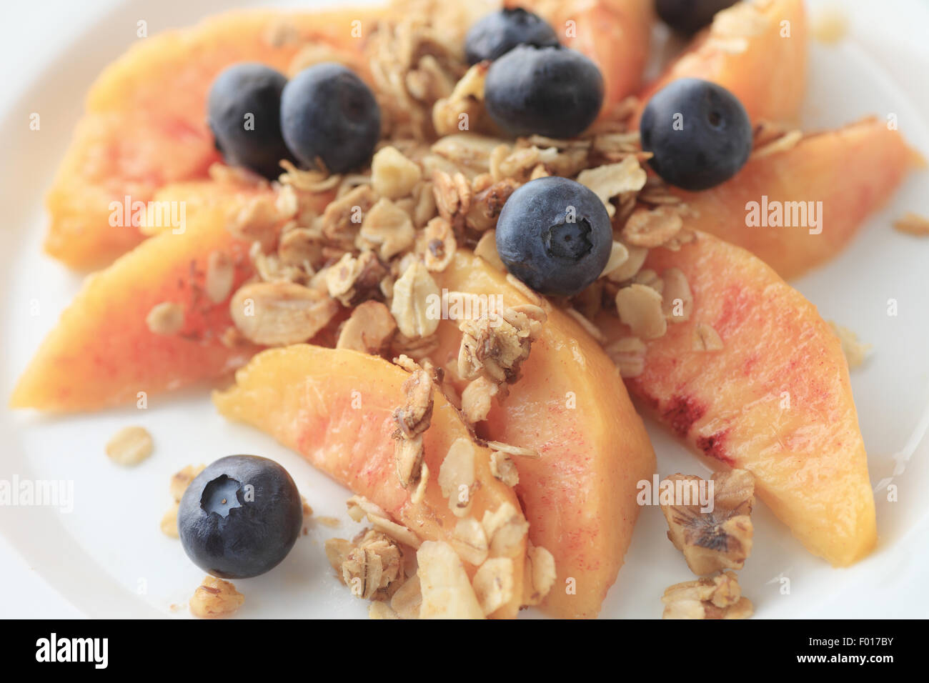 Tranches de pêches et de bleuets frais saupoudré de muesli Banque D'Images