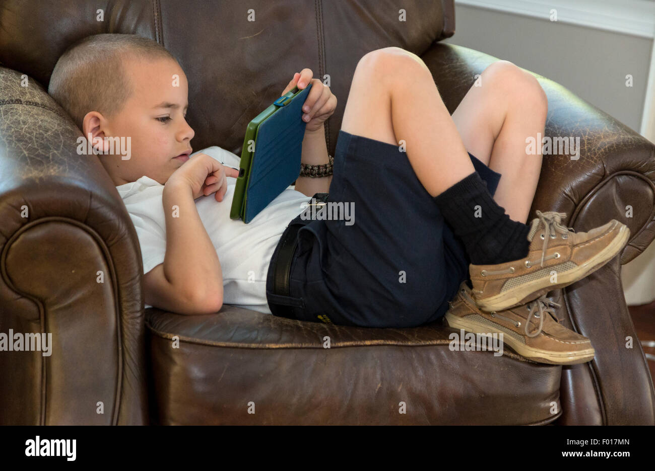 Jeune garçon (7 ans) Jouer à un jeu vidéo sur son iPad.M. Banque D'Images