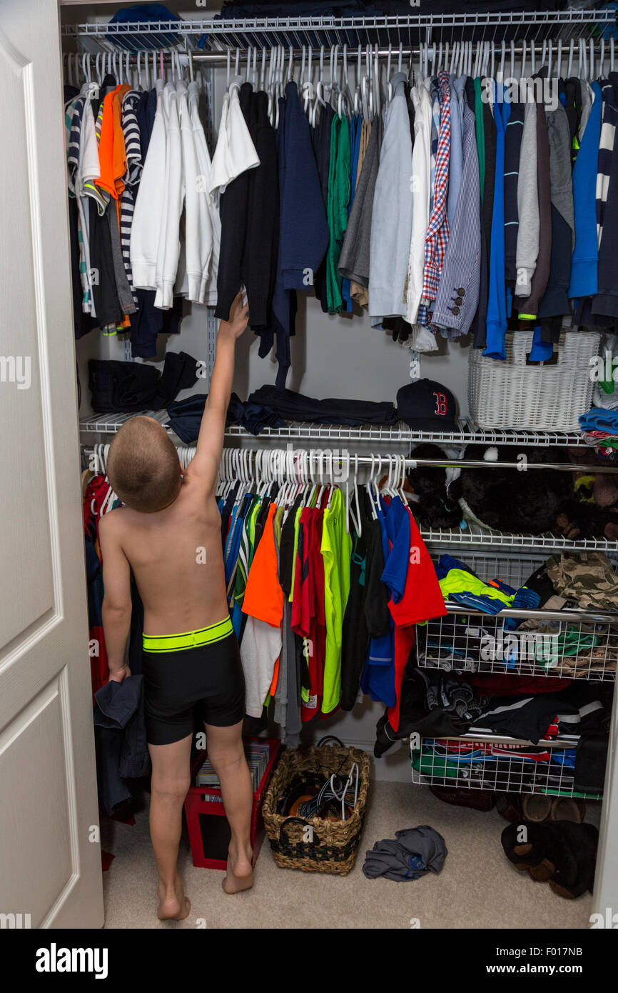Jeune garçon (7 ans) Le choix des vêtements à porter à l'école le matin. M. Banque D'Images