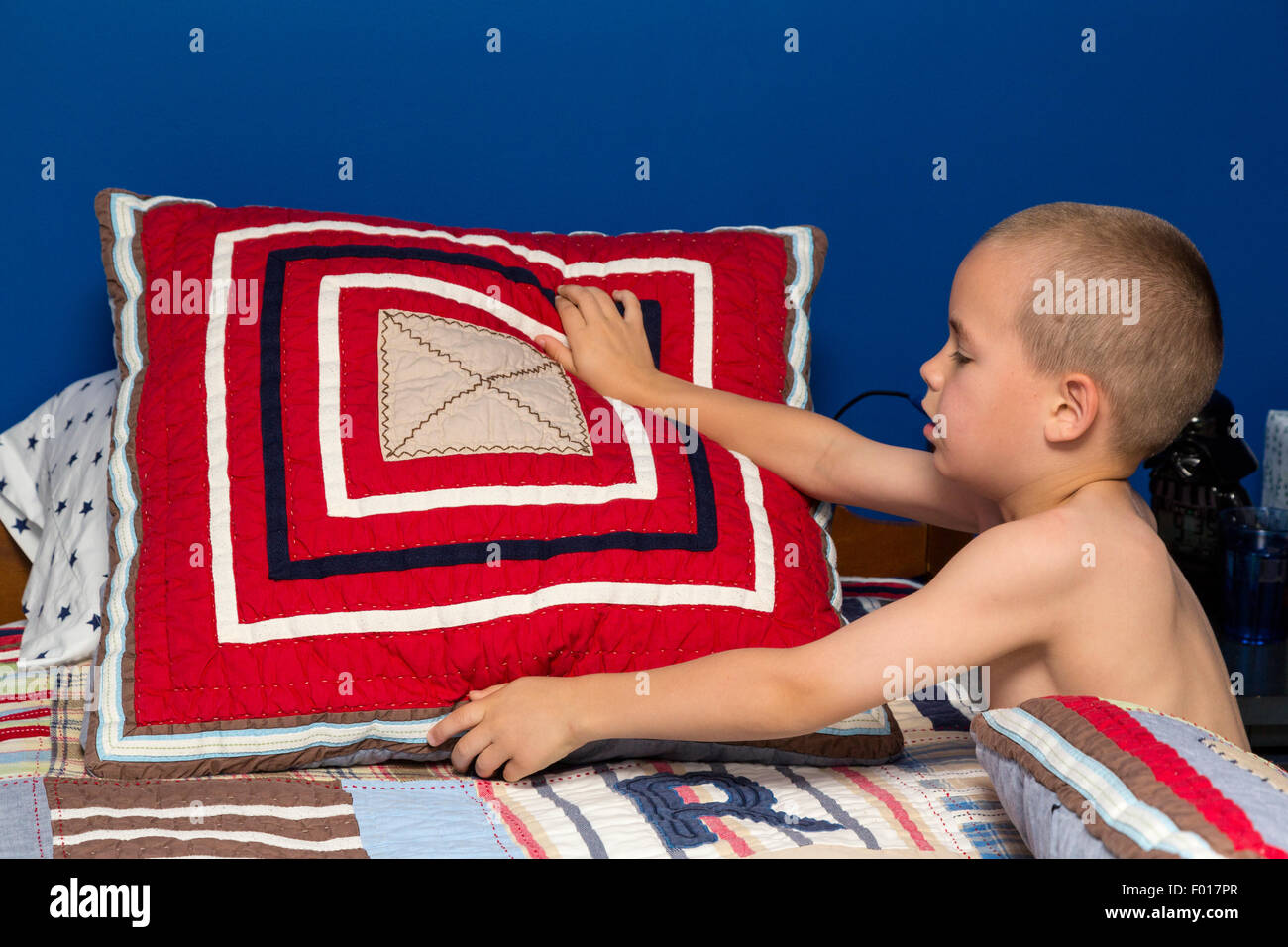Jeune garçon (7 ans) de faire son lit le matin. M. Banque D'Images