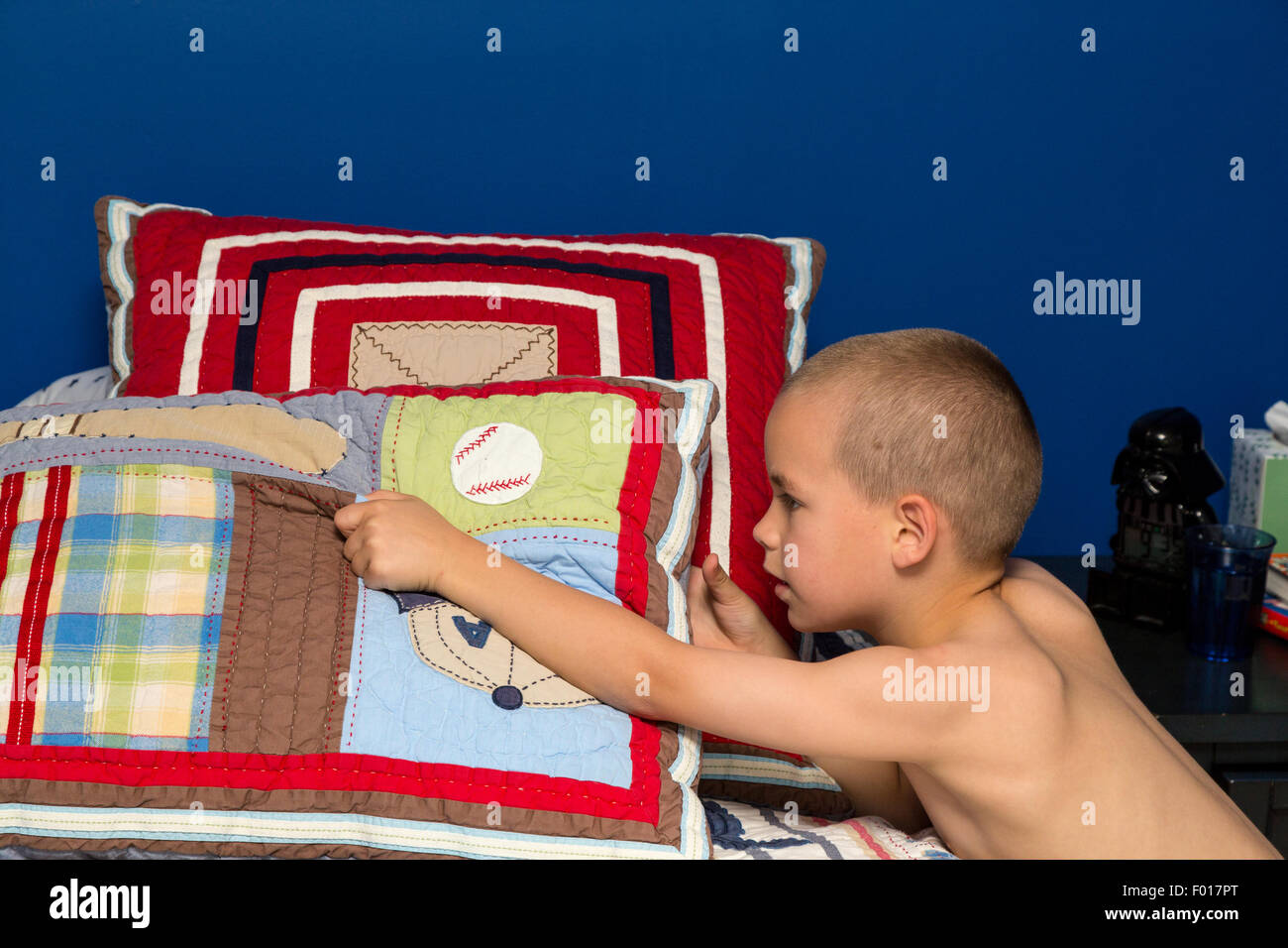 Jeune garçon (7 ans) de faire son lit le matin. M. Banque D'Images