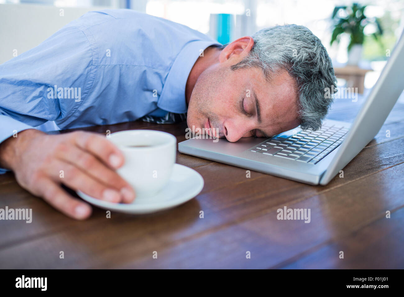 Businessman sleeping sur ordinateur portable et toucher Coffee cup Banque D'Images
