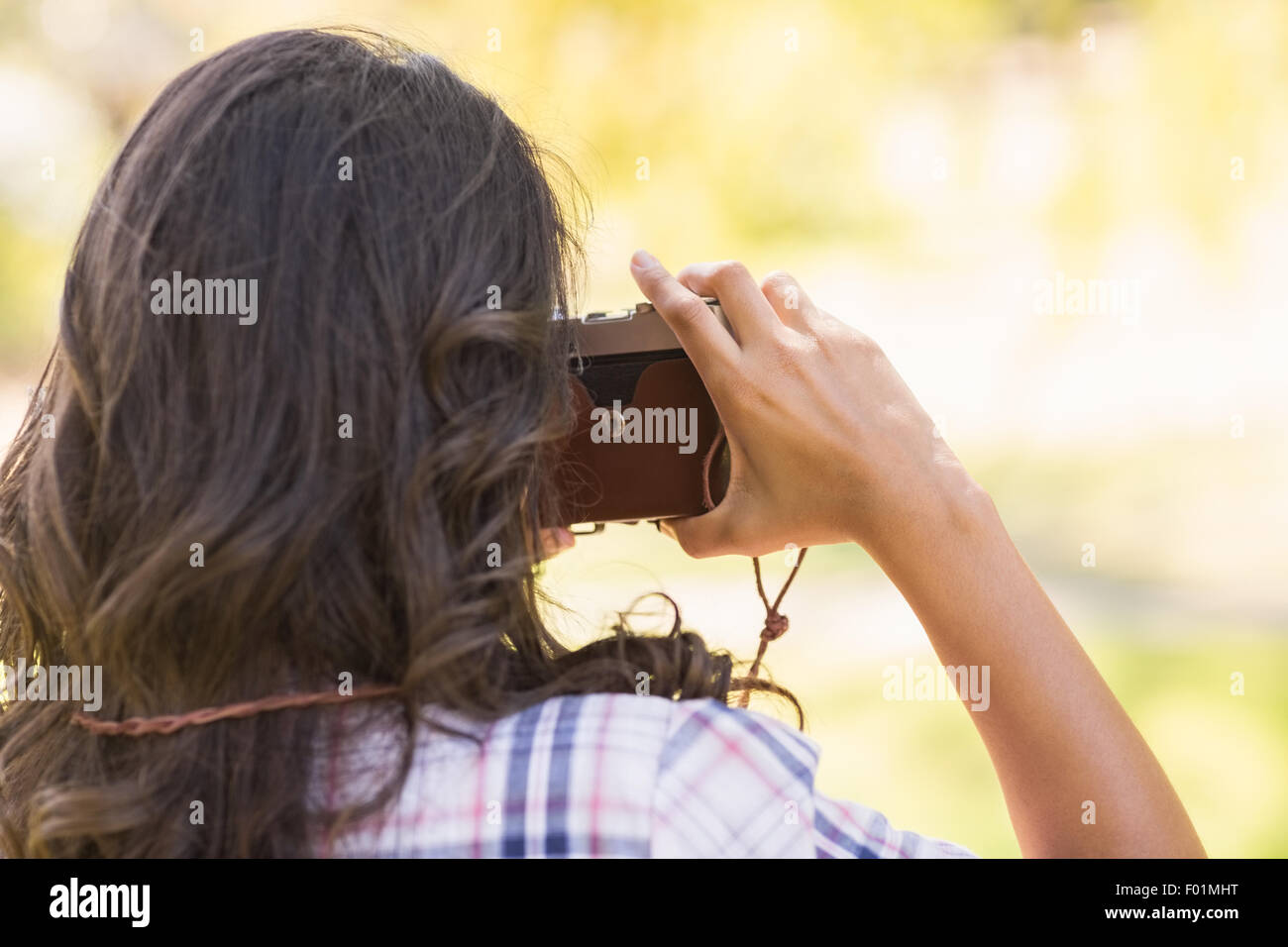 Vue arrière du belle brune dans le parc à l'aide de l'appareil photo rétro Banque D'Images