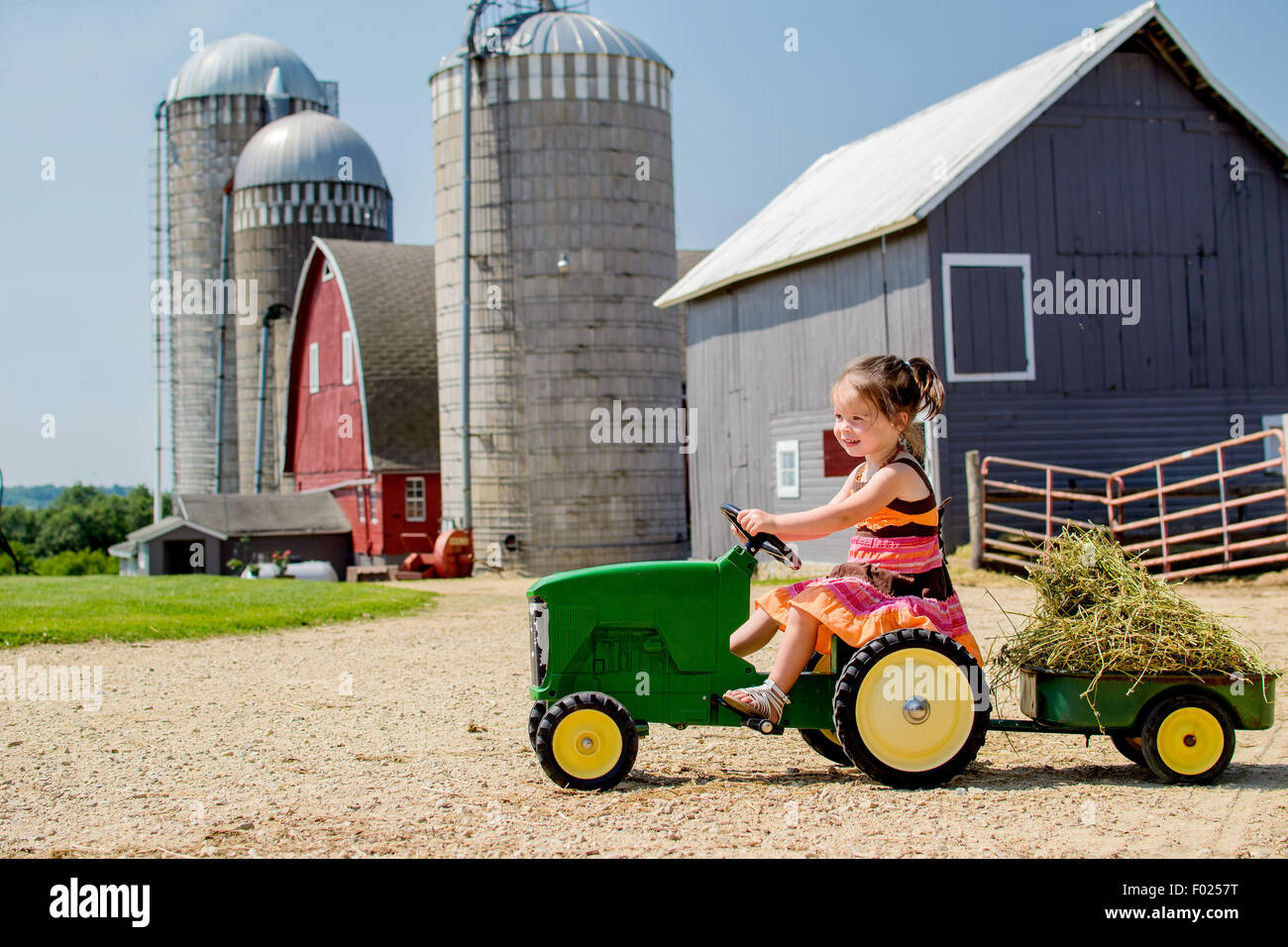 L'enseignement primaire âgés de conduire son tracteur jouet de fille Banque D'Images