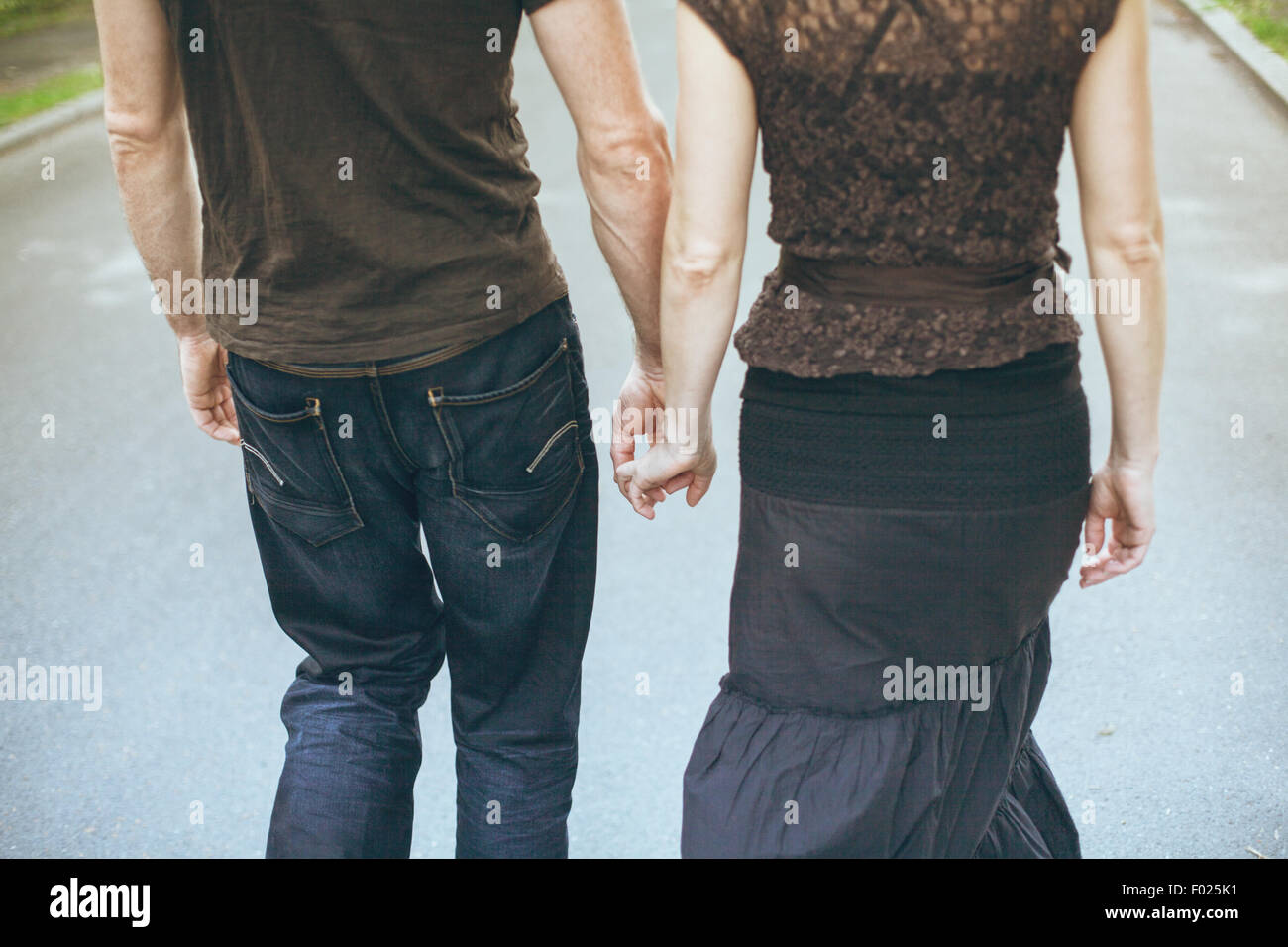 Vue arrière d'un couple holding hands, walking down street Banque D'Images