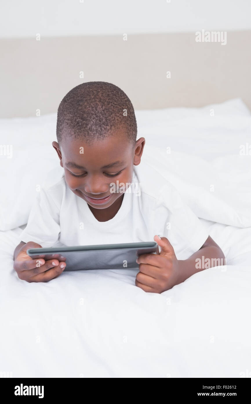 Pretty smiling little boy using digital tablet in bed Banque D'Images