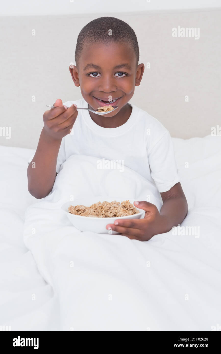 Portrait d'un joli petit garçon de manger les céréales au lit Banque D'Images