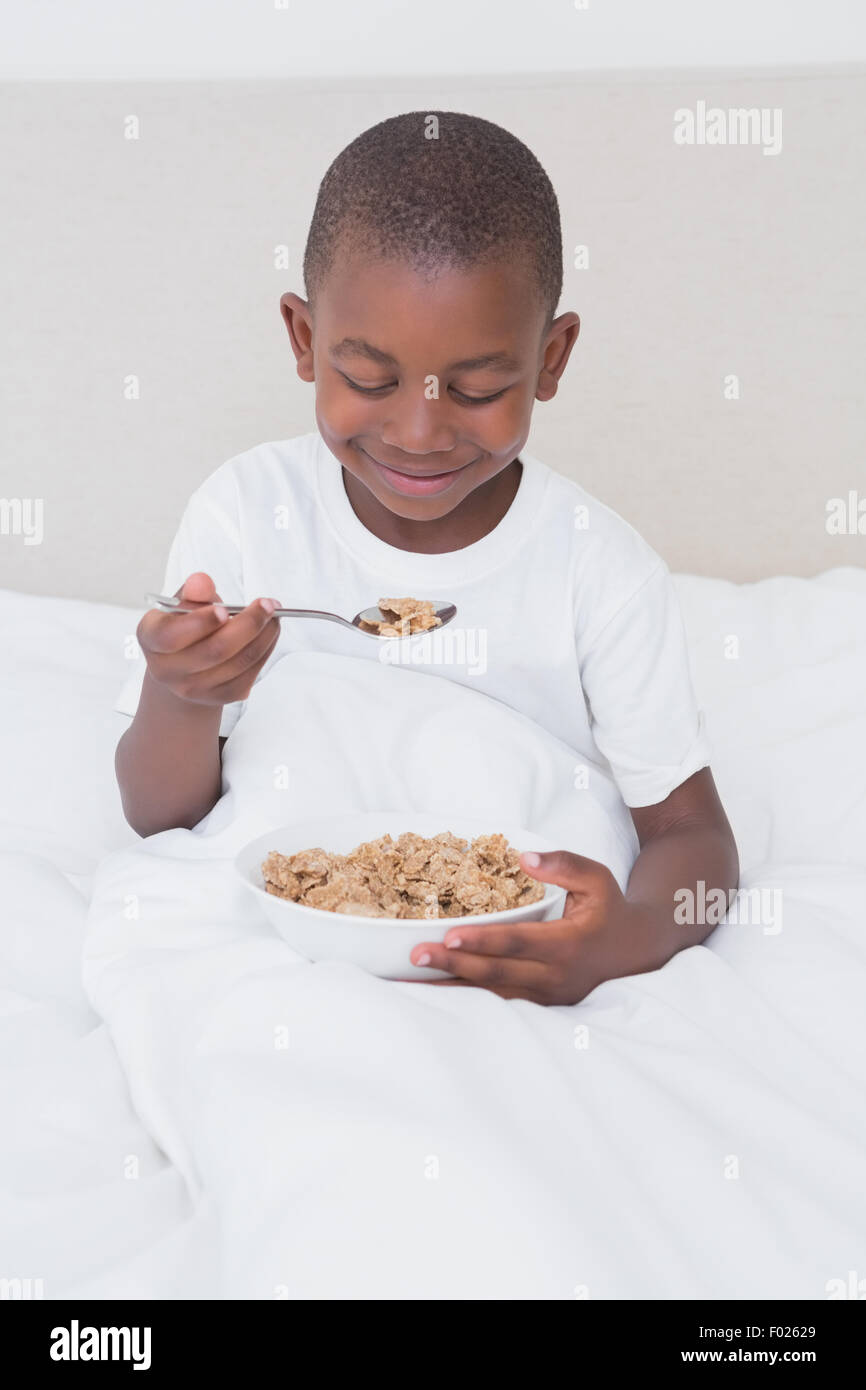 Pretty little boy eating céréales au lit Banque D'Images