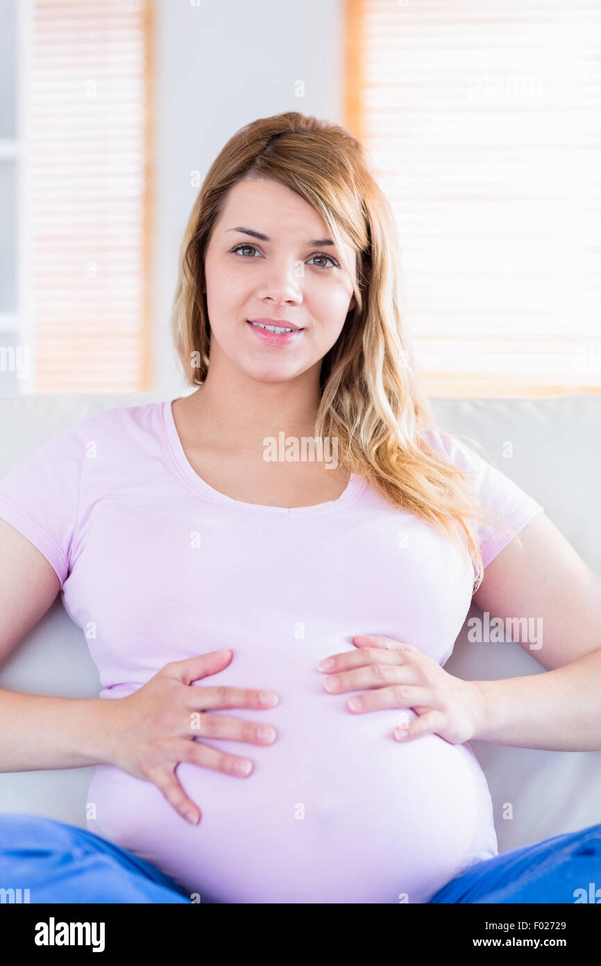 Pregnant woman looking at camera with hands on belly Banque D'Images