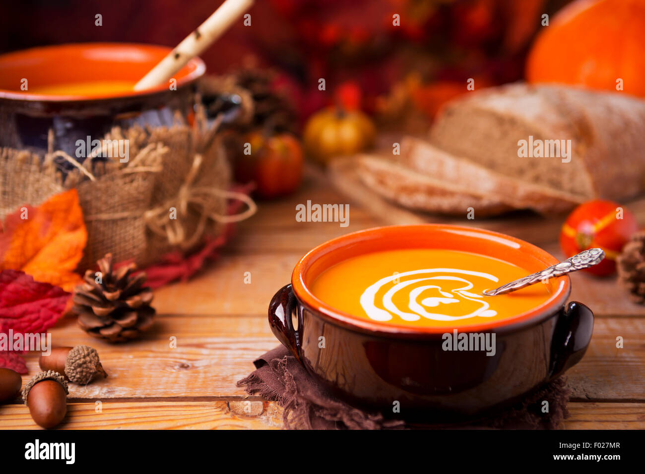 Un bol de soupe au potiron crémeuse faite maison sur une table rustique avec des décorations d'automne. Banque D'Images