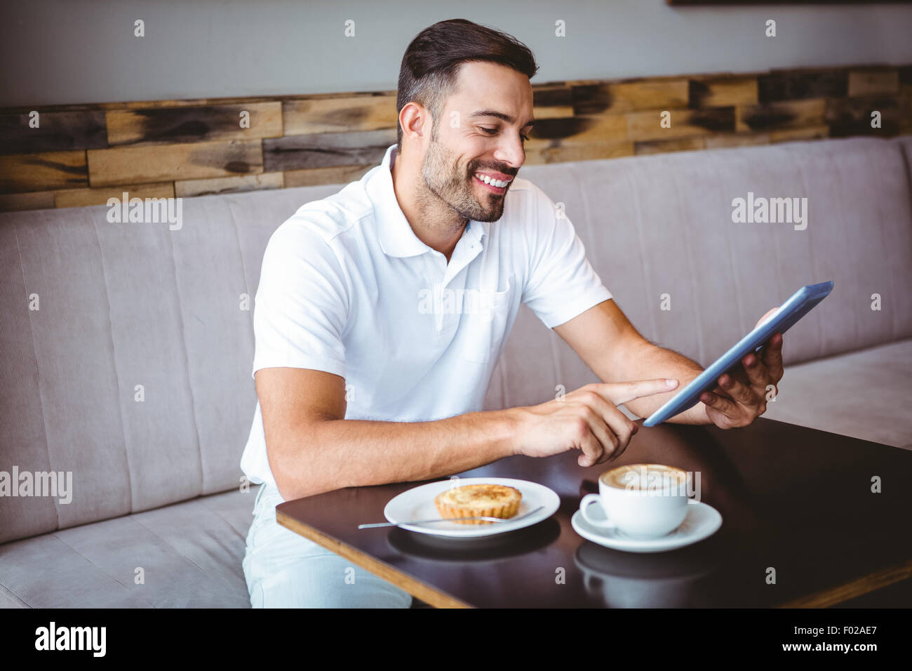 Jeune homme ayant tasse de café et pâtisserie Banque D'Images