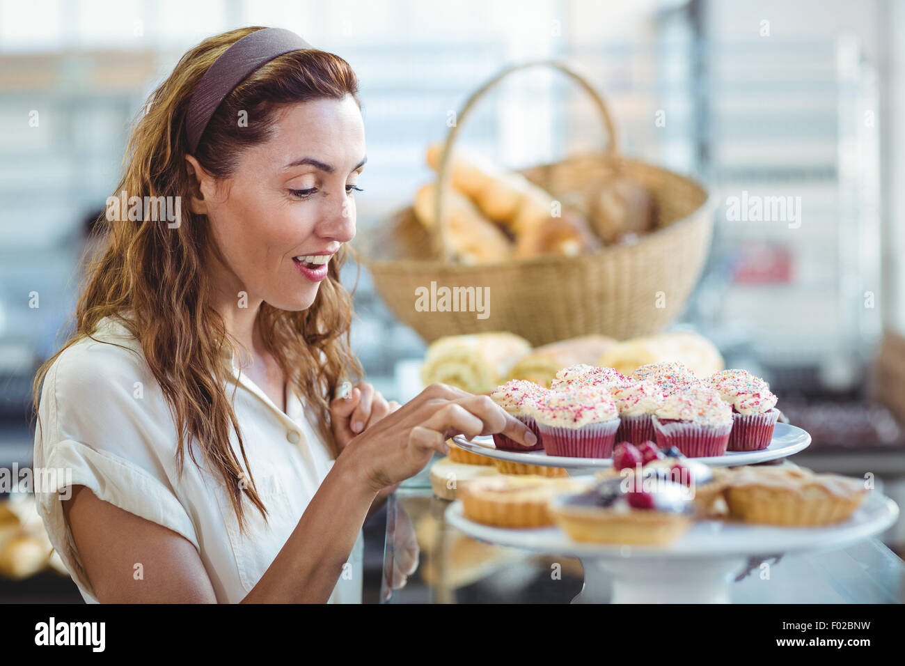 Belle brune choisissant cupcake Banque D'Images