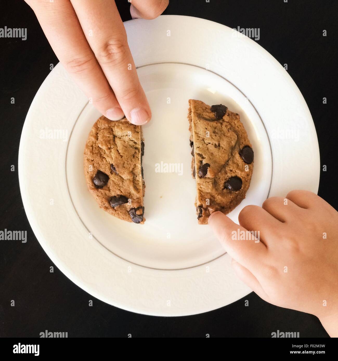 Deux personnes partageant un biscuit aux brisures de chocolat Banque D'Images