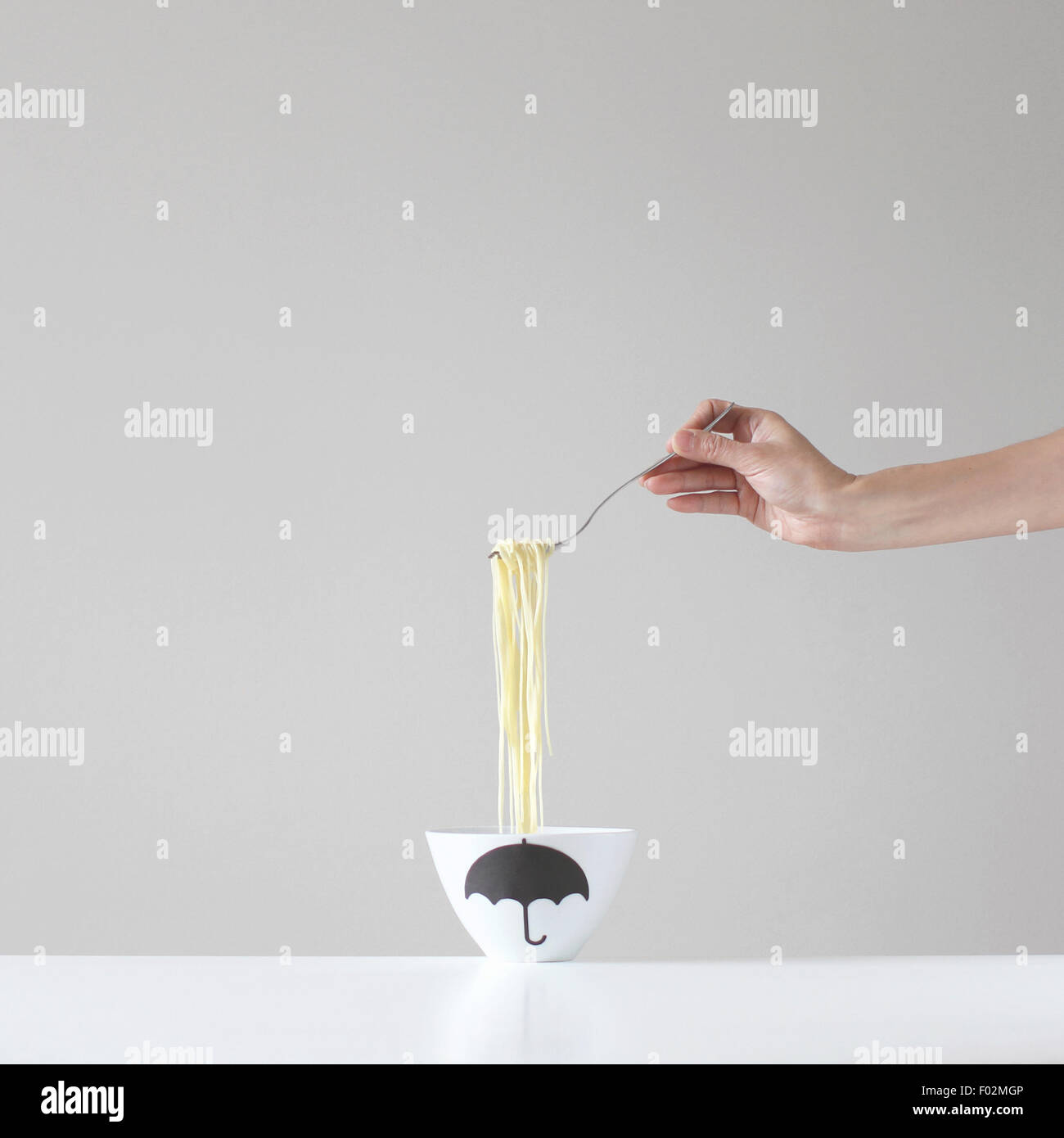 Main tenant une forkful au-dessus d'un bol de spaghetti Banque D'Images