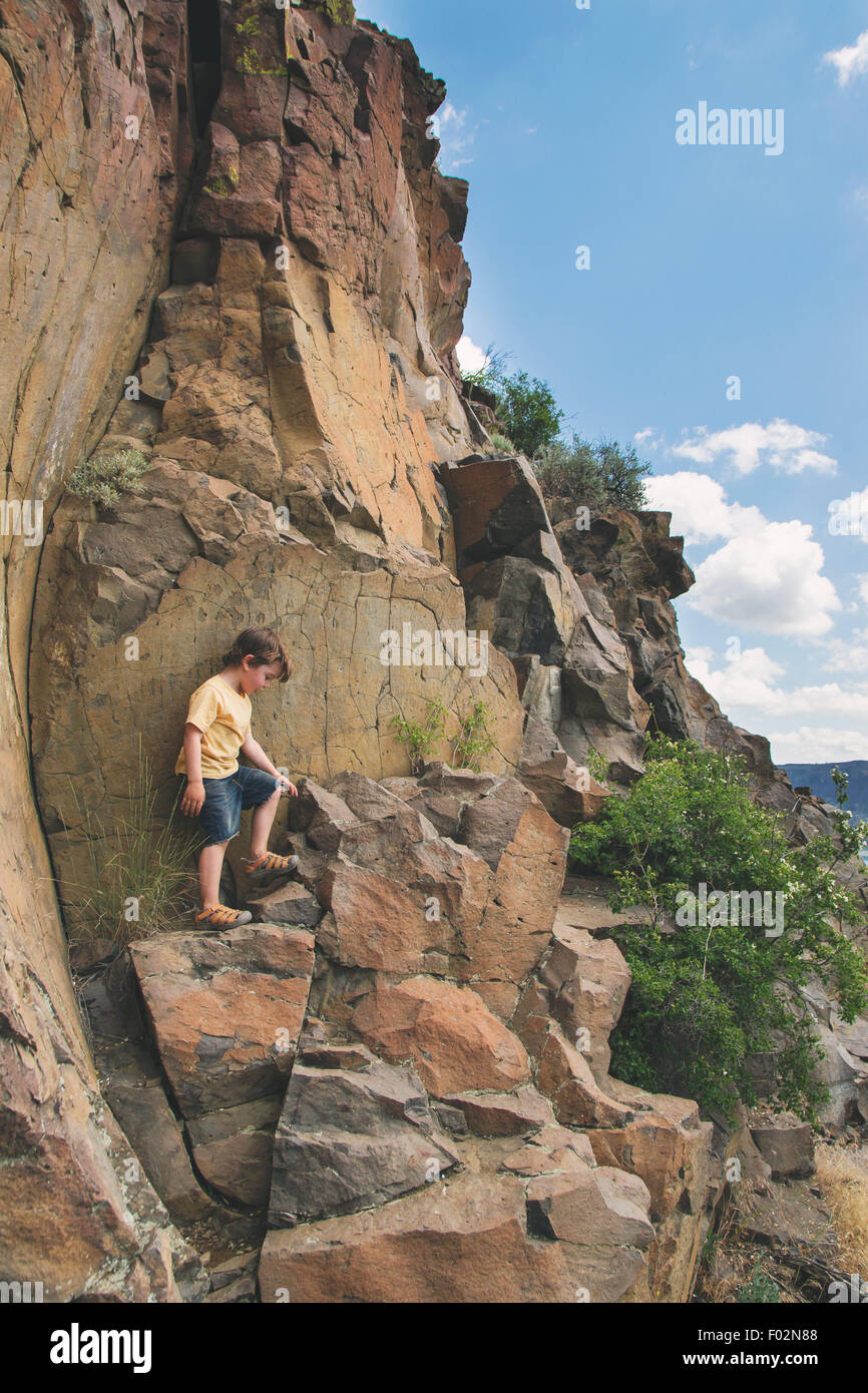 Boy climbing rocks Banque D'Images