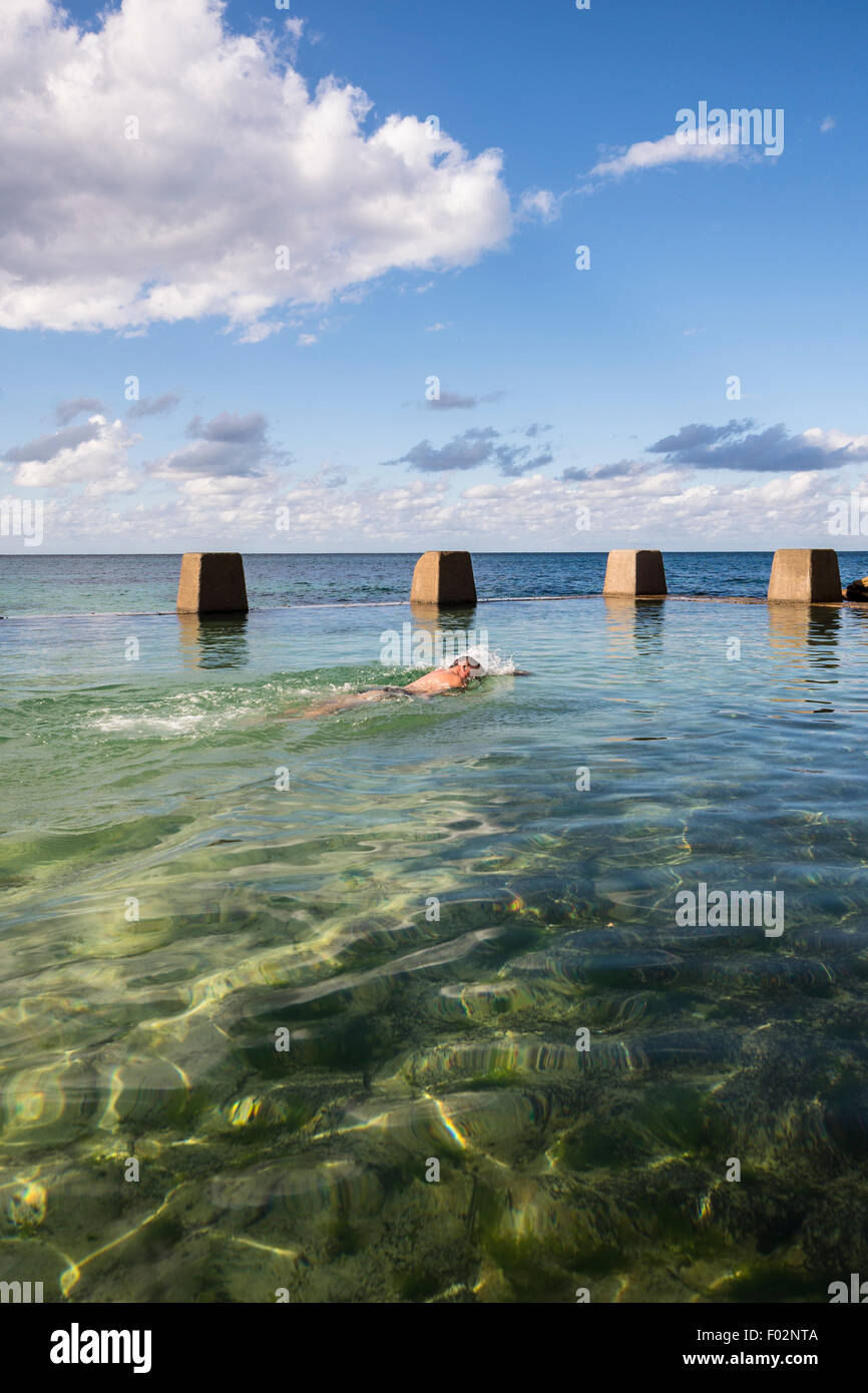 Homme natation en piscine à côté de la mer, Ross Jones Memorial Pool, Coogee Beach, Sydney, Australie Banque D'Images