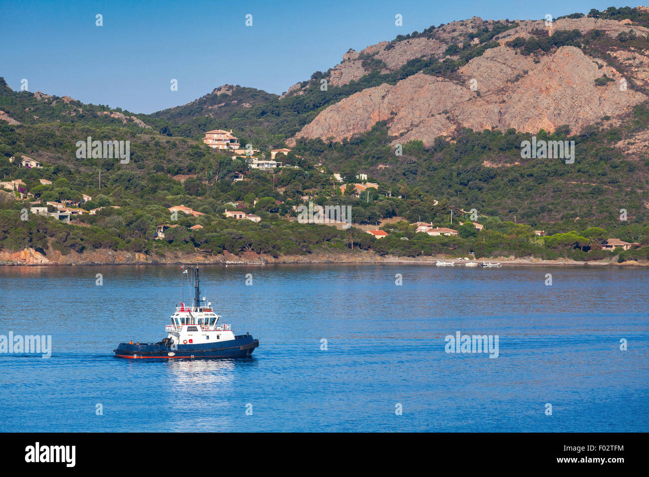 Petit bateau remorqueur avec superstructure blanc en cours sur la baie de Porto-Vecchio, Corse, France Banque D'Images