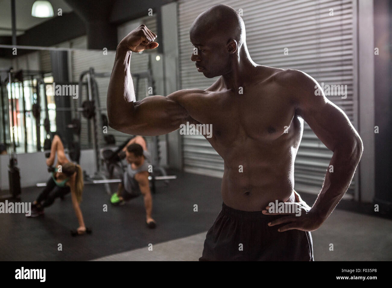 Bodybuilder jeunes posant avec ses collègues dans l'arrière-plan Banque D'Images