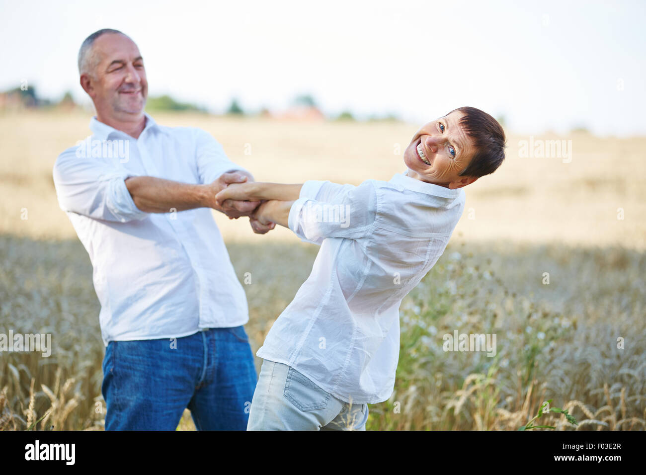 Happy senior couple dancing en été dans un champ de blé Banque D'Images