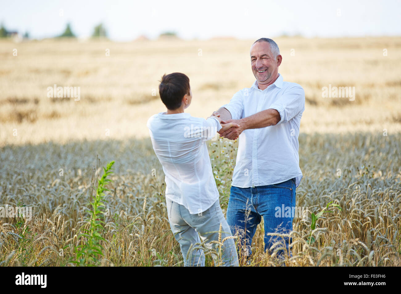 Happy senior couple dancing in champ de blé en été Banque D'Images