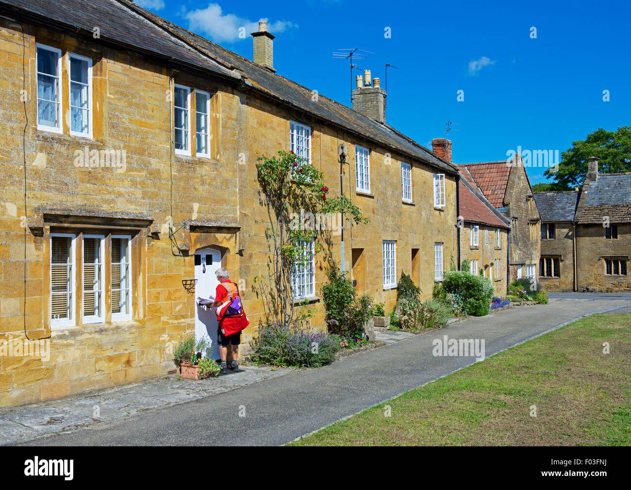 Facteur de distribuer les lettres à cottages dans le village de Montacute, Somerset, England UK Banque D'Images