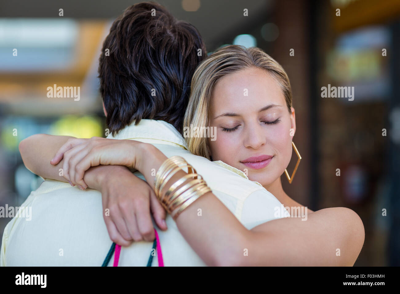Smiling woman hugging son petit ami avec les yeux fermé Banque D'Images