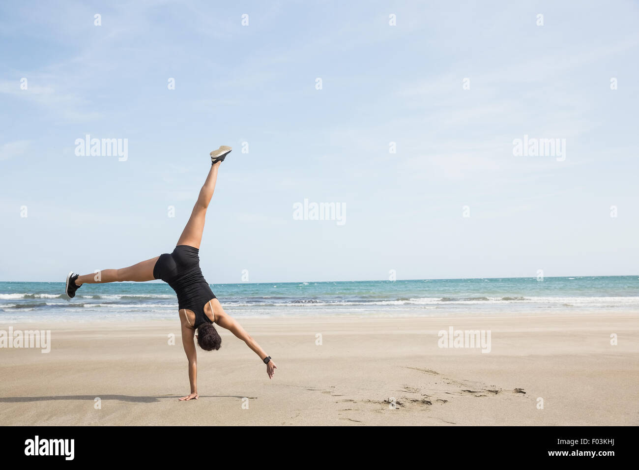 Fit woman cartwheeling sur le sable Banque D'Images